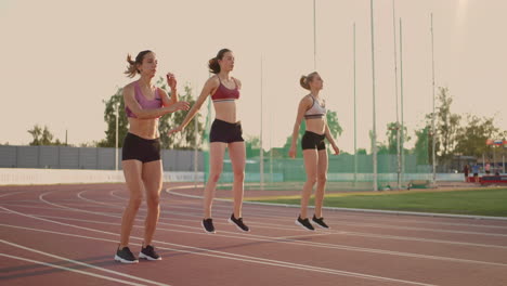 A-group-of-women-at-the-track-and-field-competition-warm-up-and-prepare-for-the-race.-Concentrating-on-the-start-line-at-the-stadium